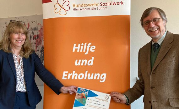 Ministerialrätin König nimmt den Reisegutschein des Bundeswehr-Sozialwerks mit großer Freude entgegen. 